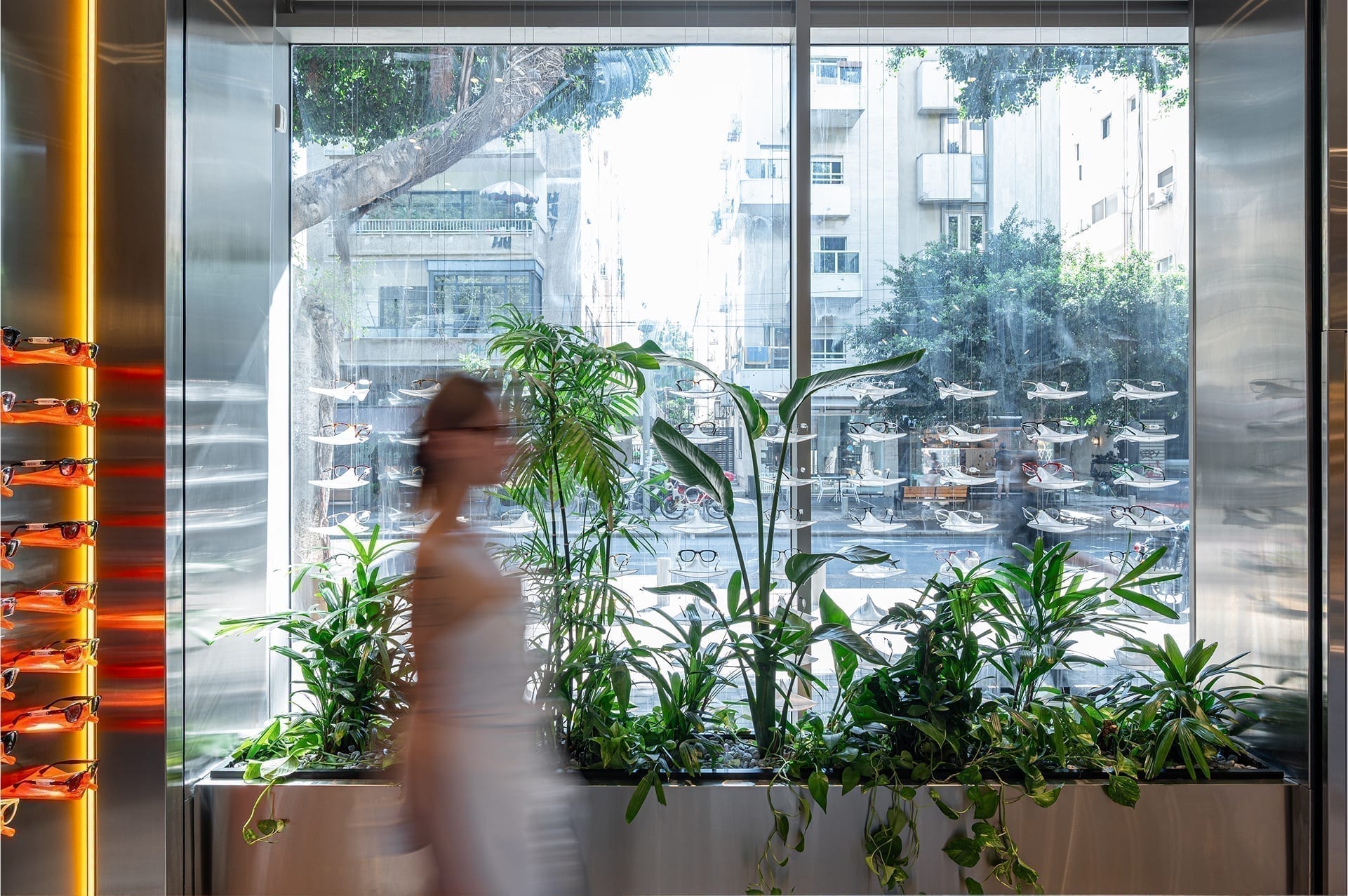 SAM&JO Eyewear Store — display wall seen through the planted storefront window